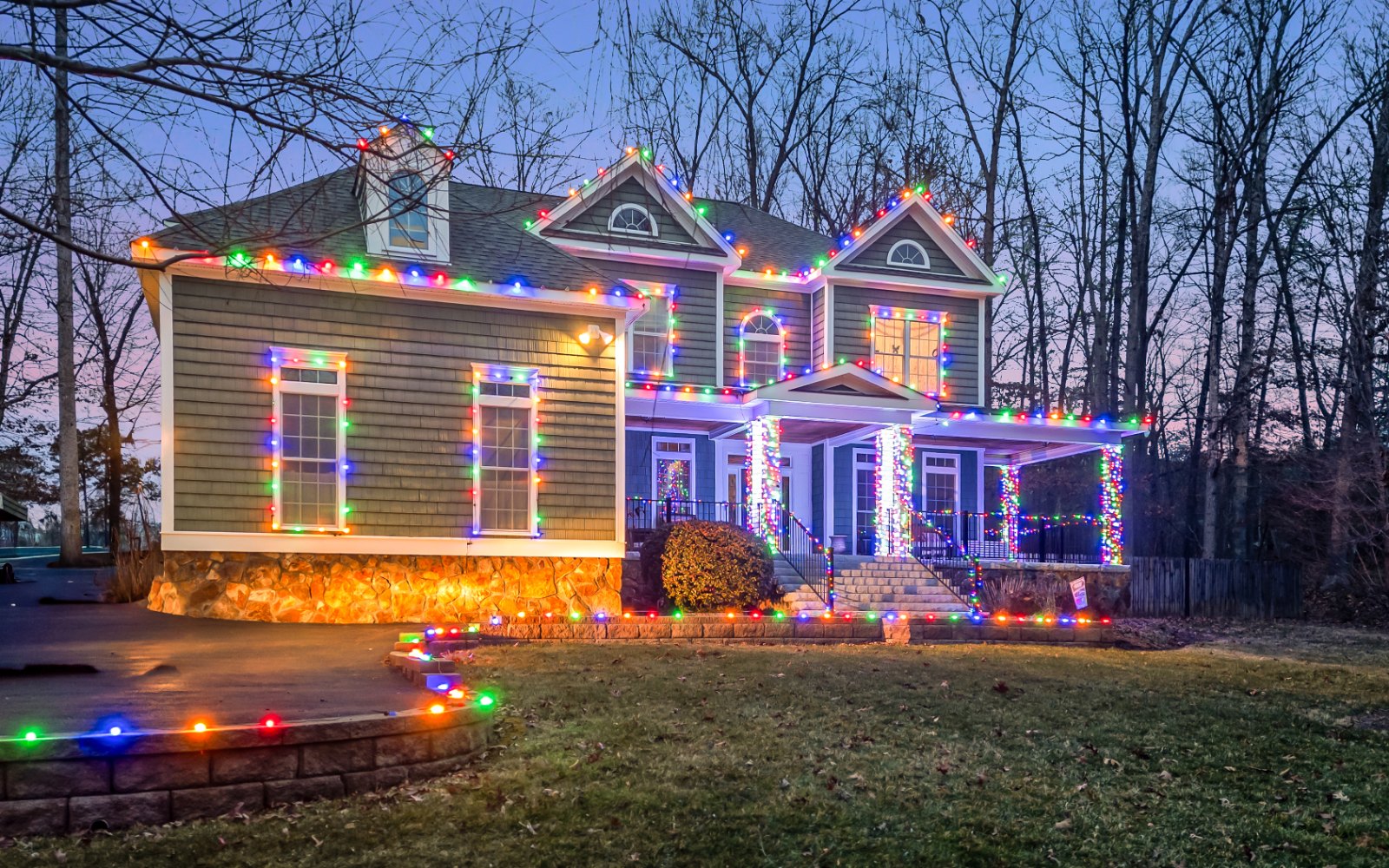 Holiday lighting on the roofline and trees of a Richmond home at dusk