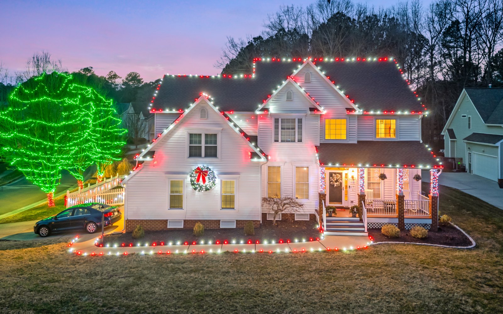 Christmas light installation on a Chesterfield, VA home — a white two-story with a red-and-white roofline and green-wrapped trees at the curb